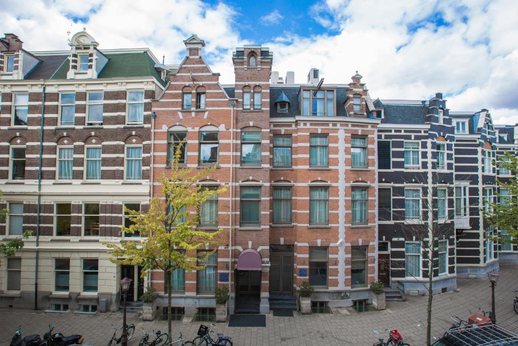 un gran edificio de ladrillo con bicicletas estacionadas frente a él en Hotel Roemer Amsterdam en Ámsterdam