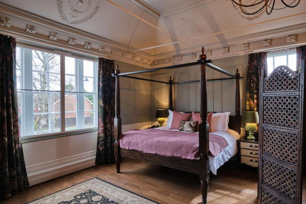 a bedroom with a four poster bed and windows at The Bulls Head Hotel in Bromley