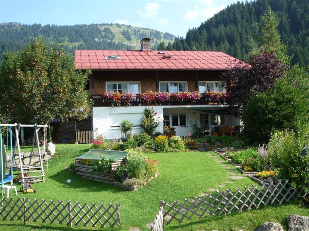 ein Haus mit einem roten Dach und einem Garten in der Unterkunft Jagdhaus Hiemer in Balderschwang