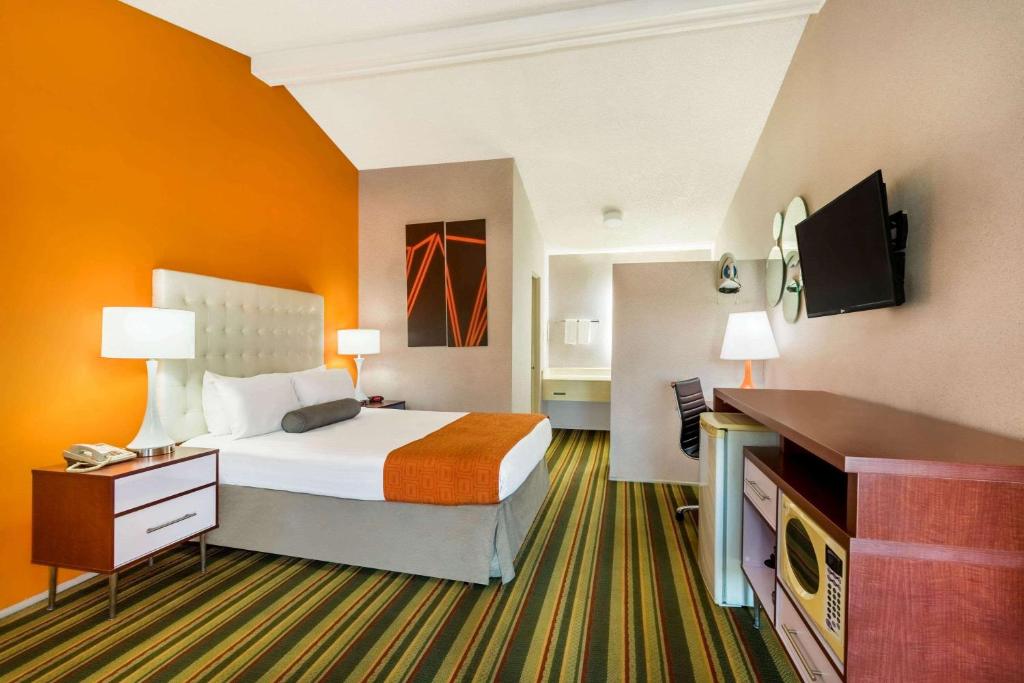 um quarto de hotel com uma cama e uma televisão de ecrã plano em Howard Johnson by Wyndham Phoenix Airport/Downtown Area em Phoenix