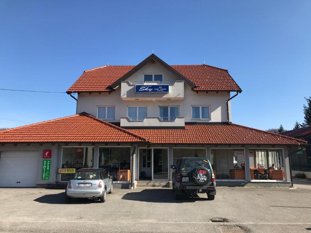 ein Gebäude mit zwei Autos auf einem Parkplatz in der Unterkunft Sobe Sky in Fužine