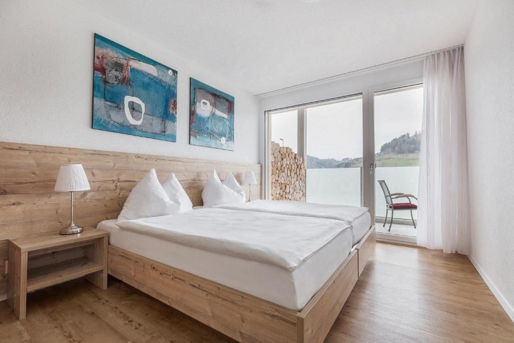 a bedroom with a large bed and a large window at Aparthotel Wiggertal - Self Check-in in Dagmersellen