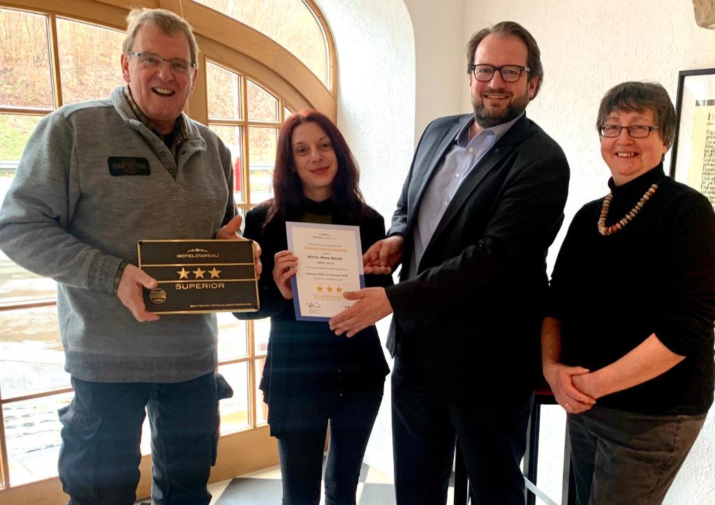 eine Gruppe von drei Personen, die eine Tafel hochhalten in der Unterkunft Hotel Haus Recke in Balve