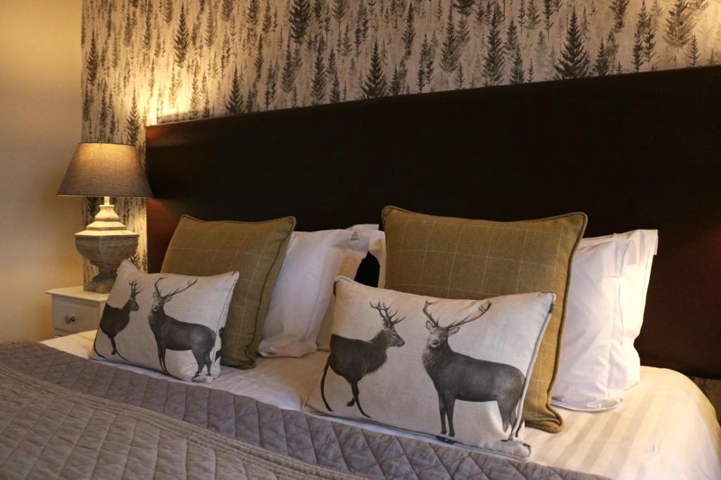 a bed with four pillows with deer on it at No12 Hotel in North Berwick