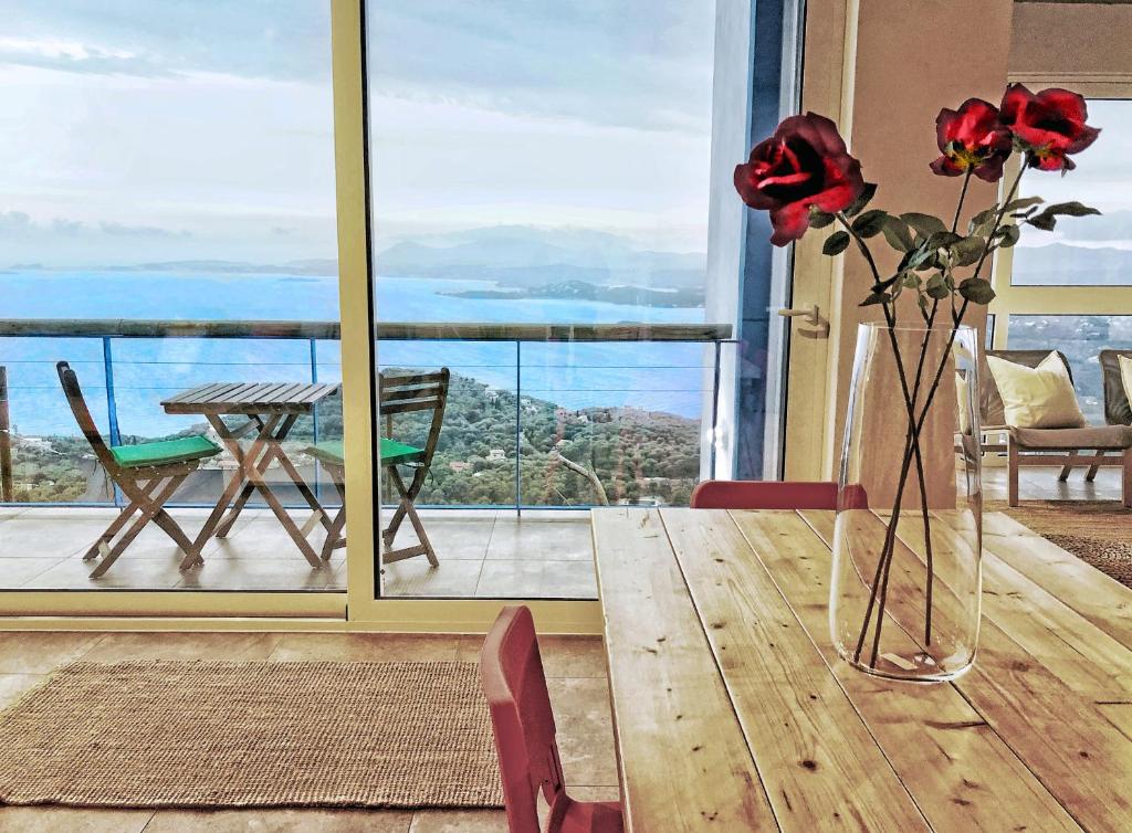 un vase avec des fleurs sur une table en bois avec vue dans l'établissement House Sienna of Villa Intaba Best Views Corfiot Riviera Corfu Island Greece Contemporary Design Pool with Spectacular Sea VIEWS close to Ipsos Beach, à Corfou