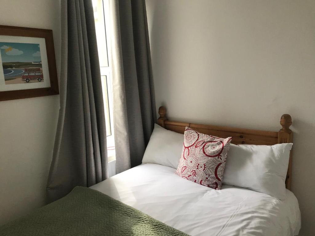 a bed with a pillow on it next to a window at Rolling Wave Guesthouse in Bundoran