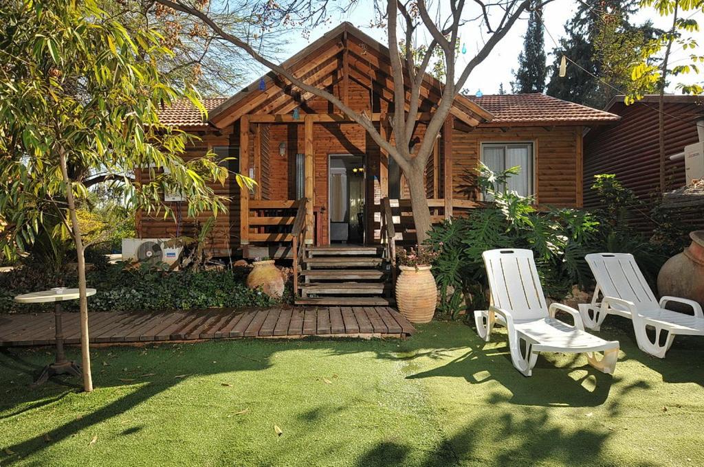 uma pequena casa com duas cadeiras e um alpendre em איתן בקתות עץ Eitan Wood Cabins Resort em Sede Eli‘ezer