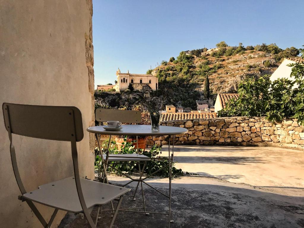 a table and a chair sitting next to a building at IL CORVO DI PIETRA in Scicli