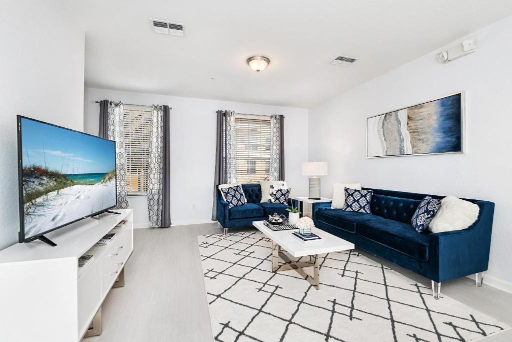ein Wohnzimmer mit einem blauen Sofa und einem TV in der Unterkunft Updated Vista Cay Townhome, 10 min from Universal in Orlando