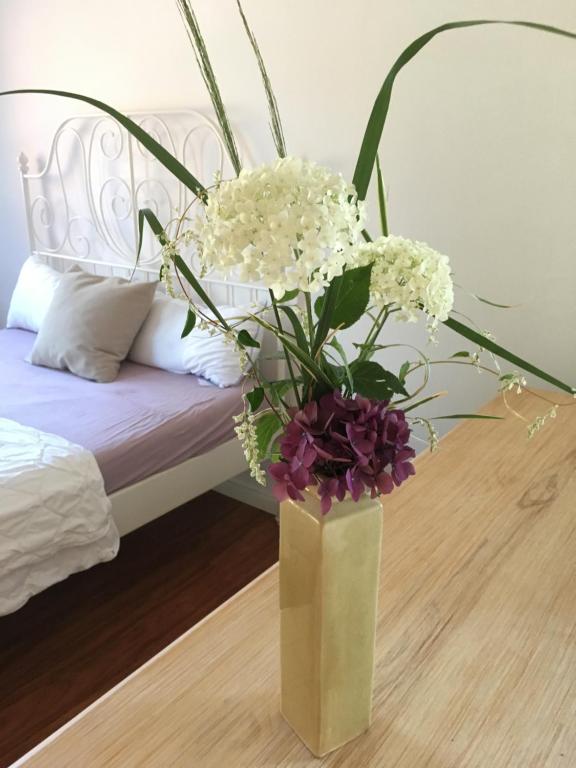 a vase with flowers on a table next to a bed at Idyllisches Wohnen in Bad Bramstedt in Bad Bramstedt