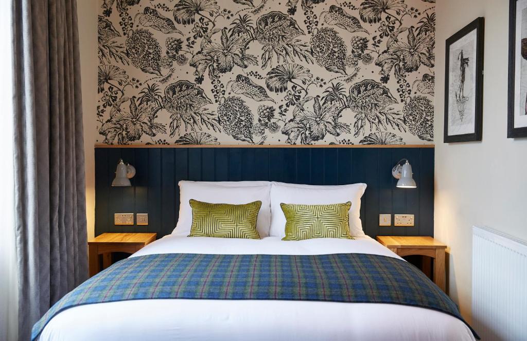 a bedroom with a bed with a blue head board at Pen and Parchment by Greene King Inns in Stratford-upon-Avon