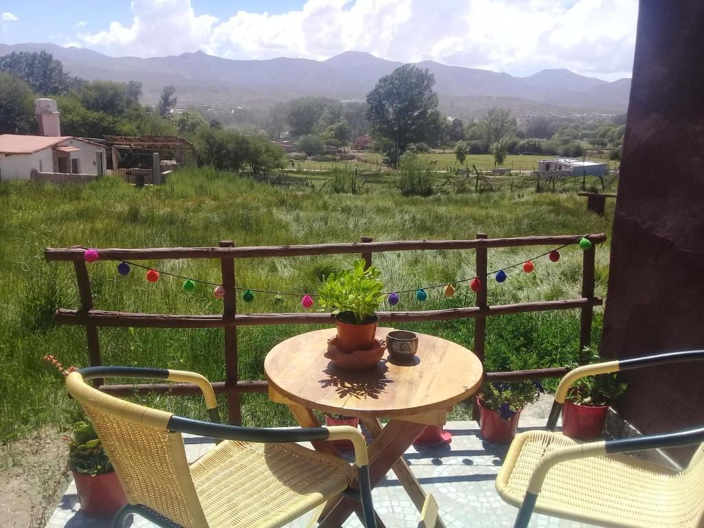 a table and chairs on a porch with a view of a field at El Cardón,habitación privada en el campo in Humahuaca