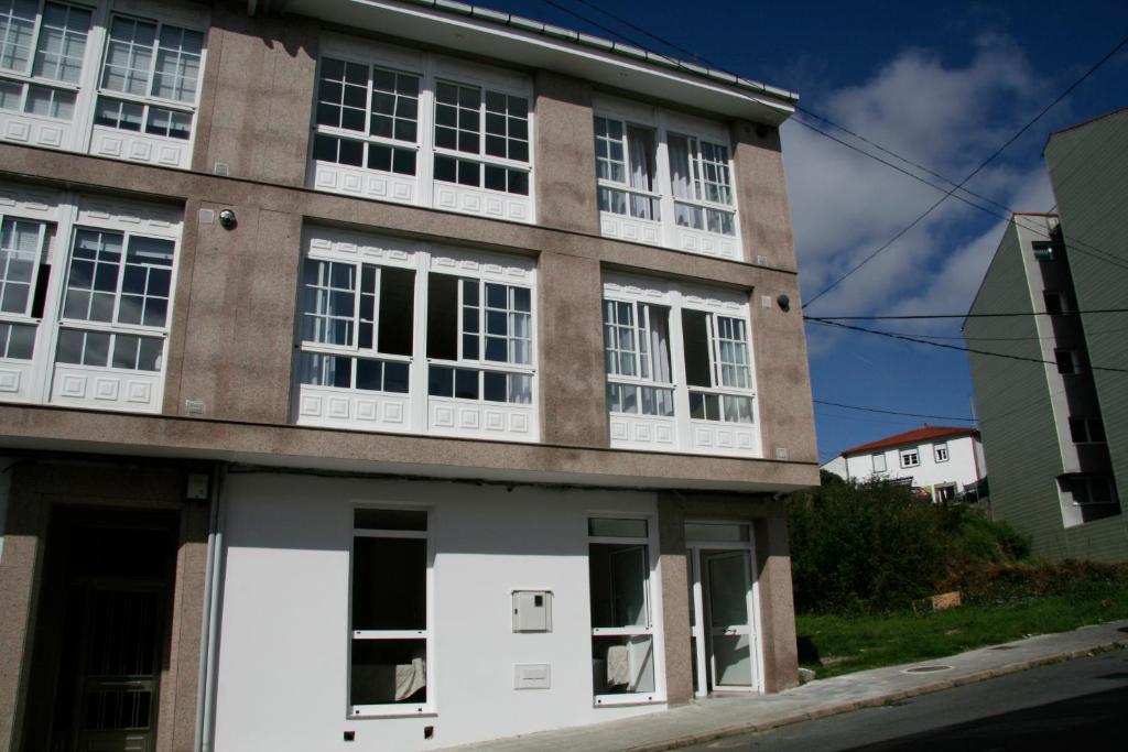 a building with white windows on a street at Lar do Peregrino in Palas de Rei