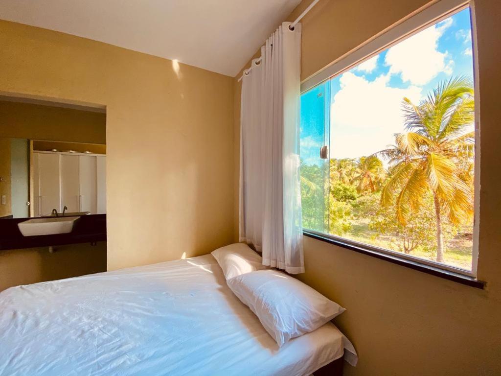 a bedroom with a window with a view of a palm tree at Casa em flecheiras com piscina in Flecheiras