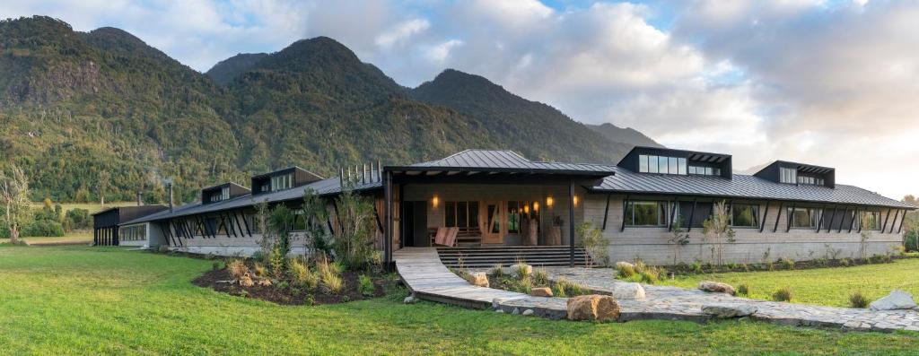 a house in a field with mountains in the background at Futangue Hotel & Spa in Lago Ranco