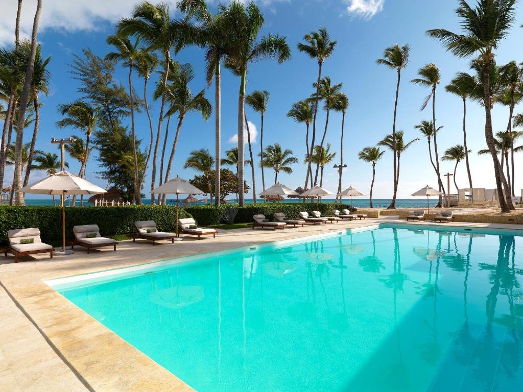 a swimming pool with palm trees and the ocean at Meliá Punta Cana Beach Wellness Inclusive - Adults only in Punta Cana