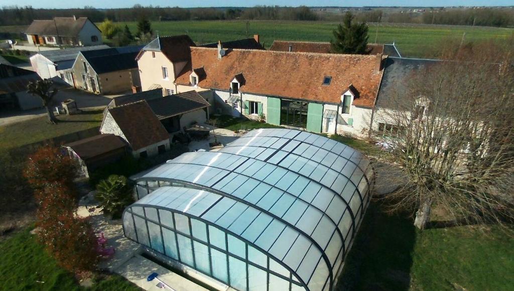 eine Luftansicht eines Hauses mit einem Gewächshaus aus Glas in der Unterkunft La Ferme de Couffy in Couffy
