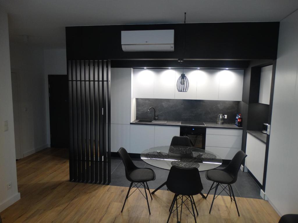 kuchnia ze stołem i czarnymi krzesłami w obiekcie Black&White Apartment Bis - Małe Garbary 8 w Poznaniu