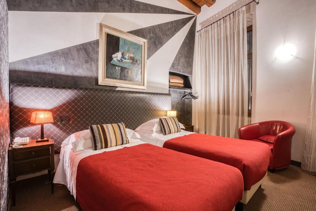 una camera d'albergo con due letti e una sedia di Boutique Hotel Scalzi - Adults Only a Verona