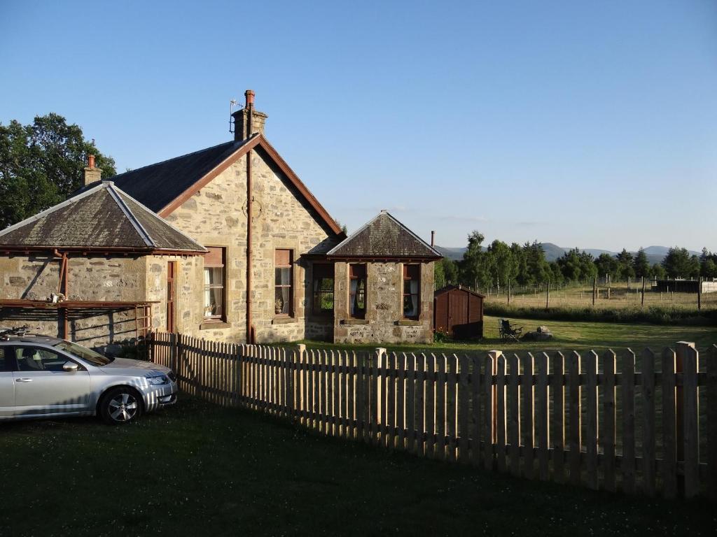 una casa con una valla y un coche delante de ella en Shetland Cottage Kincraig, en Kincraig