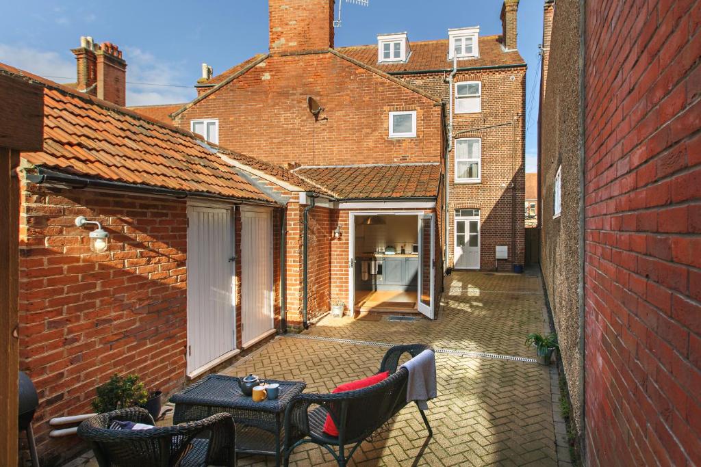 an outdoor patio with tables and chairs in a brick building at The Sands Sheringham in Sheringham