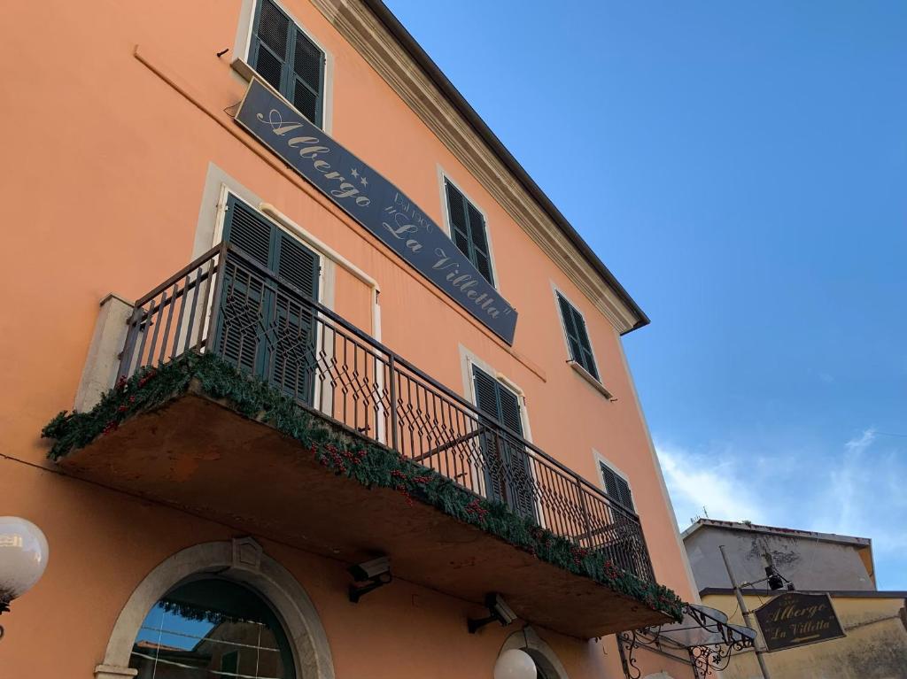 un edificio con balcón y una señal en él en Albergo La Villetta, en Sarzana