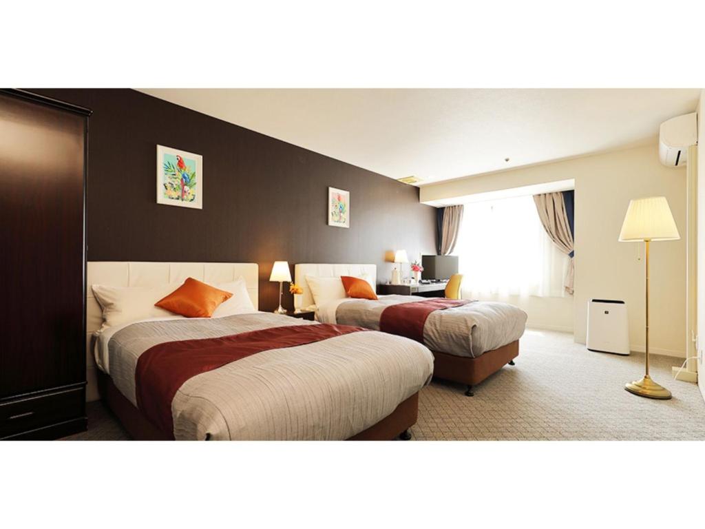 a hotel room with two beds and a window at Garden hotel Shiunkaku Higashimatsuyama / Vacation STAY 77481 in Higashimatsuyama