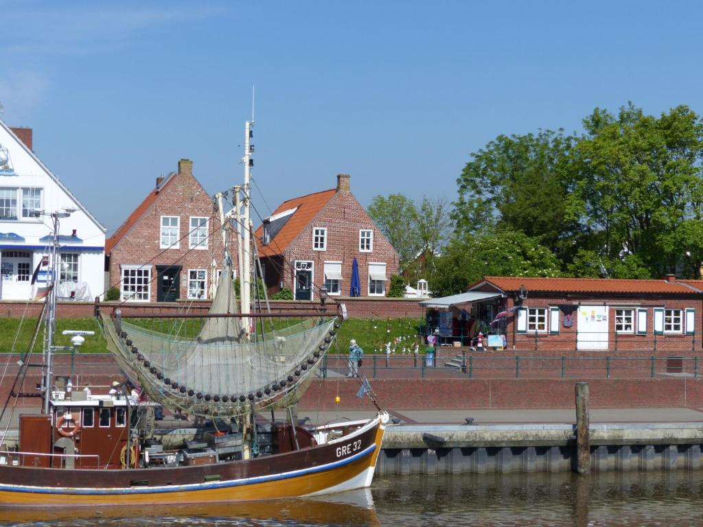 ein Boot im Wasser neben einem Dock in der Unterkunft Hafenblick Greetsiel in Greetsiel