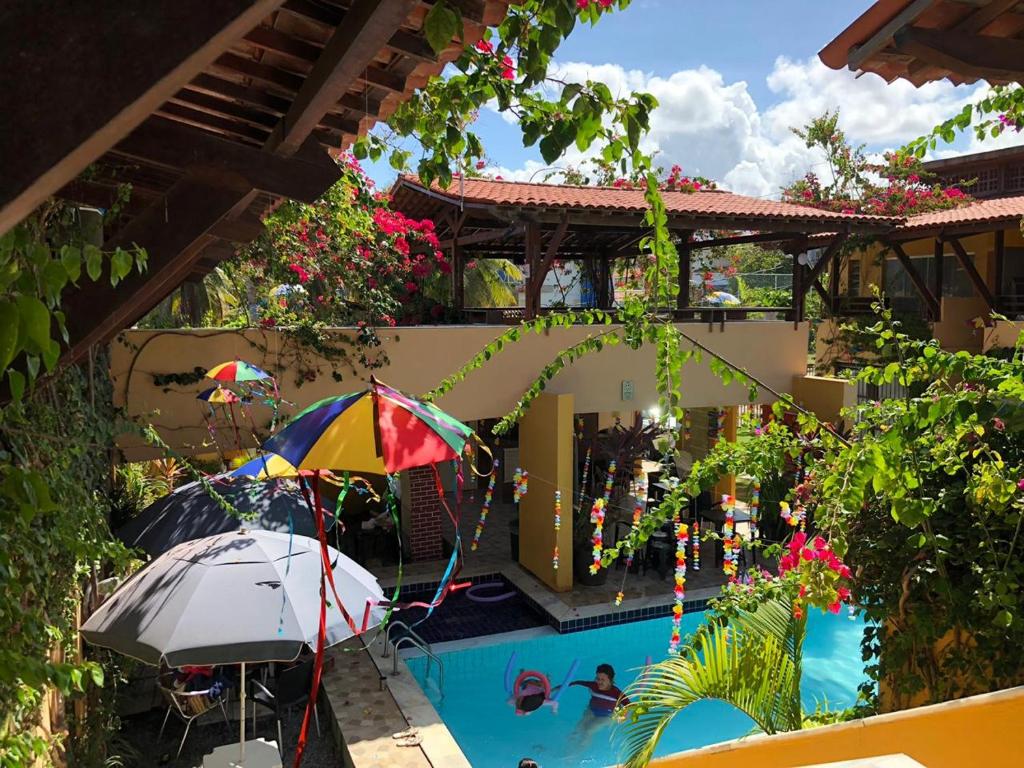 a pool with an umbrella and people in a swimming pool at Ap Beirar Mar com Piscina in Cabo de Santo Agostinho