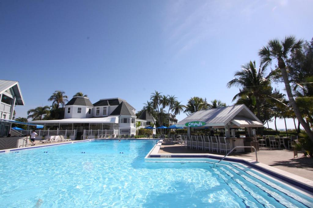 a large swimming pool with palm trees and houses at Casa Ybel Resort in Sanibel