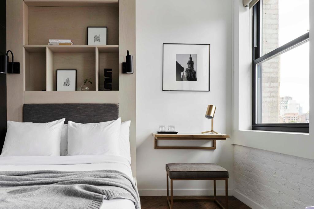 a bedroom with a bed and a chair and a window at Walker Hotel Tribeca in New York