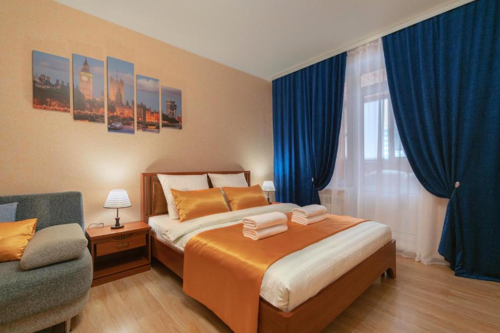 a bedroom with a large bed with blue curtains at Five Stars Argentina in Nizhnevartovsk