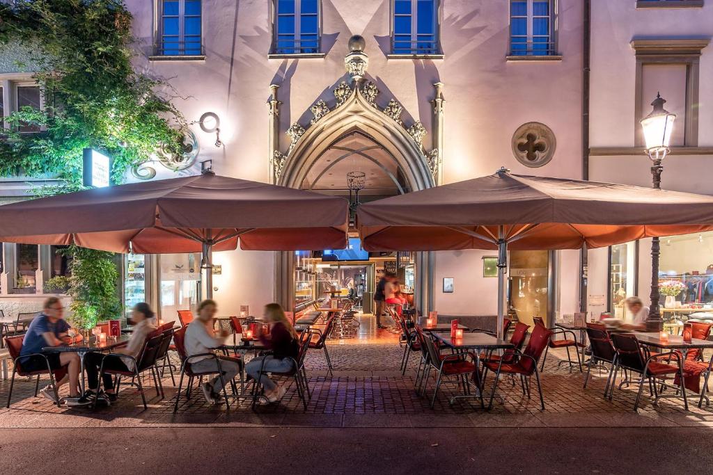 a group of people sitting at tables with umbrellas at Hotel Loge in Winterthur