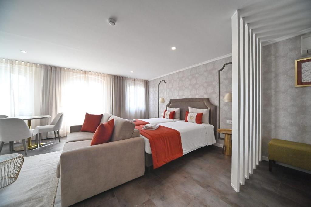 ein Schlafzimmer mit einem Bett, einer Couch und einem Tisch in der Unterkunft Famous Crows Lisbon Suites in Lissabon