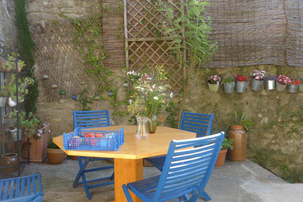 a wooden table with blue chairs and flowers on a patio at La Colline Bleue in Banne