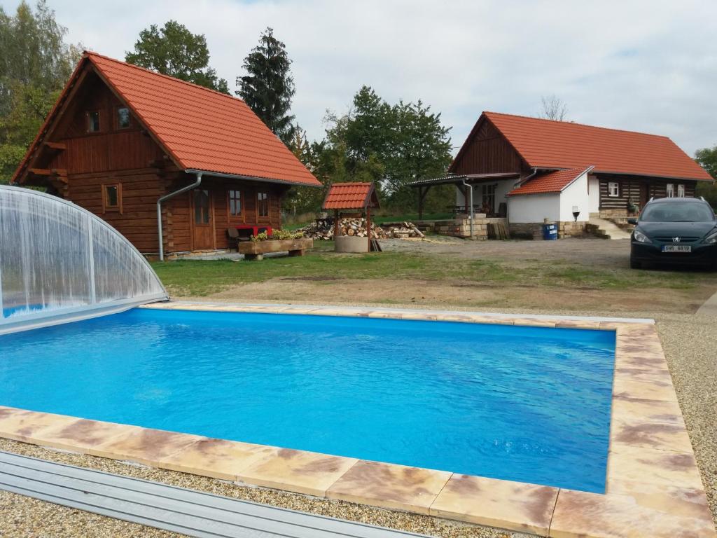 una piscina di fronte a una casa e un fienile di Chalupy Březka a Libuň