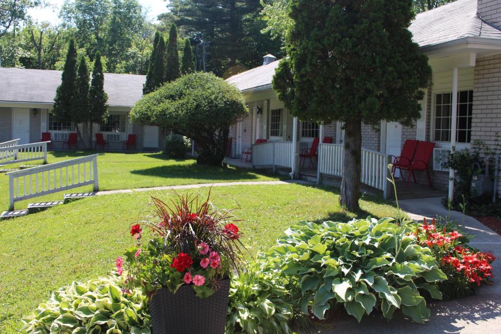 a yard with flowers and plants in front of a house at Colonial Resort-1000Islands in Gananoque
