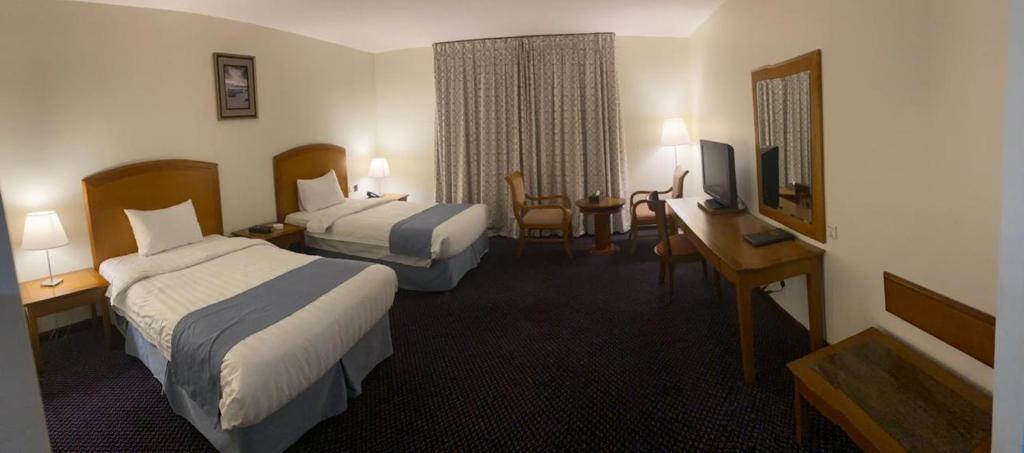 a hotel room with two beds and a desk at Doolve Hotel Al Khobar in Al Khobar