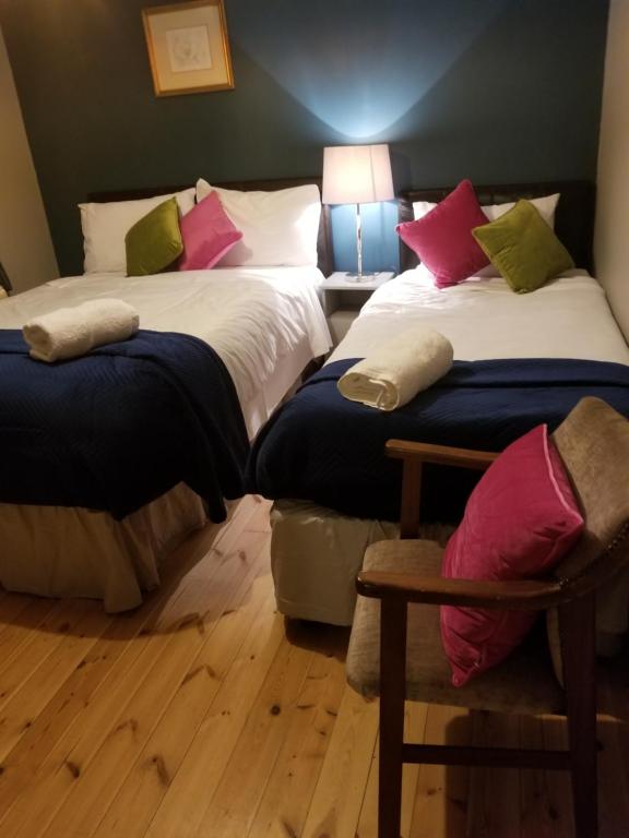 1 dormitorio con 2 camas, mesa y lámpara en Baywatch Inn en Dingle