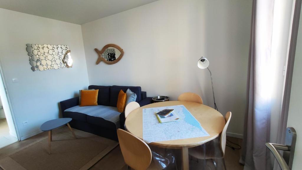 a living room with a table and a blue couch at Les Muguets in Villers-sur-Mer