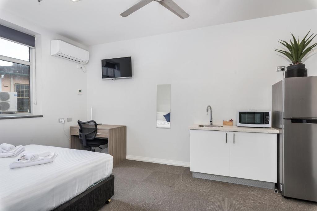 a room with a bed and a kitchen with a refrigerator at Studios on King in Newcastle