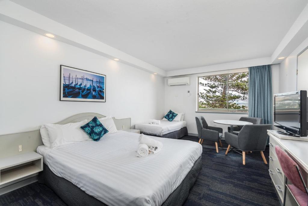 ニューカッスルにあるAlloggio Newcastle Beachのベッド2台、テーブルと椅子が備わるホテルルームです。