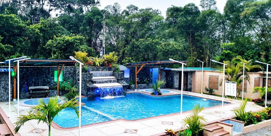 una piscina con cascada en un patio en Sisakuna Lodge, en Mindo