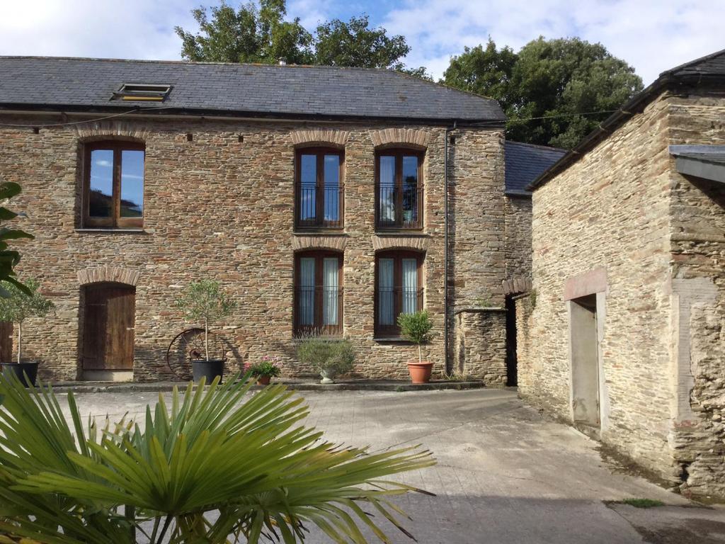 ein altes Backsteinhaus mit schwarzen Fenstern in der Unterkunft Mixit Cottage in Kingsbridge