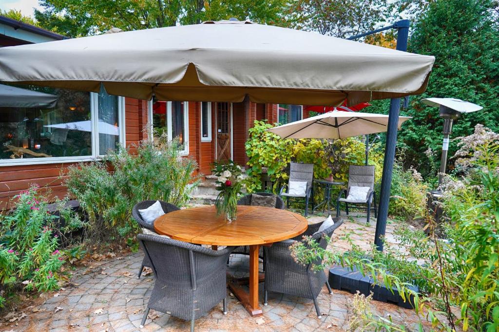 a table and chairs under a large umbrella at Gîte le 308 Chambre bord de l'eau oka in Oka