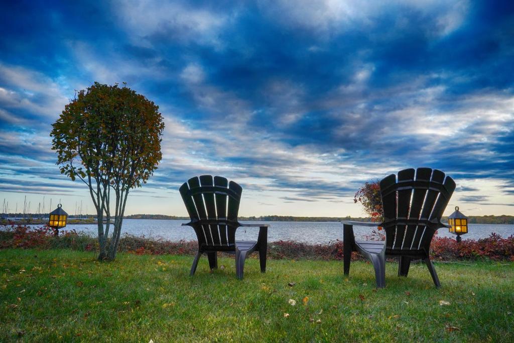 two chairs sitting in the grass near a body of water at Gîte le 308 Chambre bord de l'eau oka in Oka