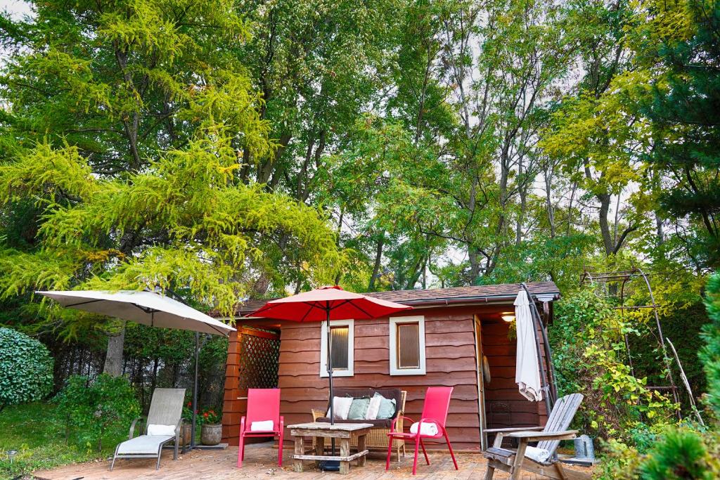 a small cabin with chairs and a table and an umbrella at Gîte le 308 Chambre bord de l'eau oka in Oka