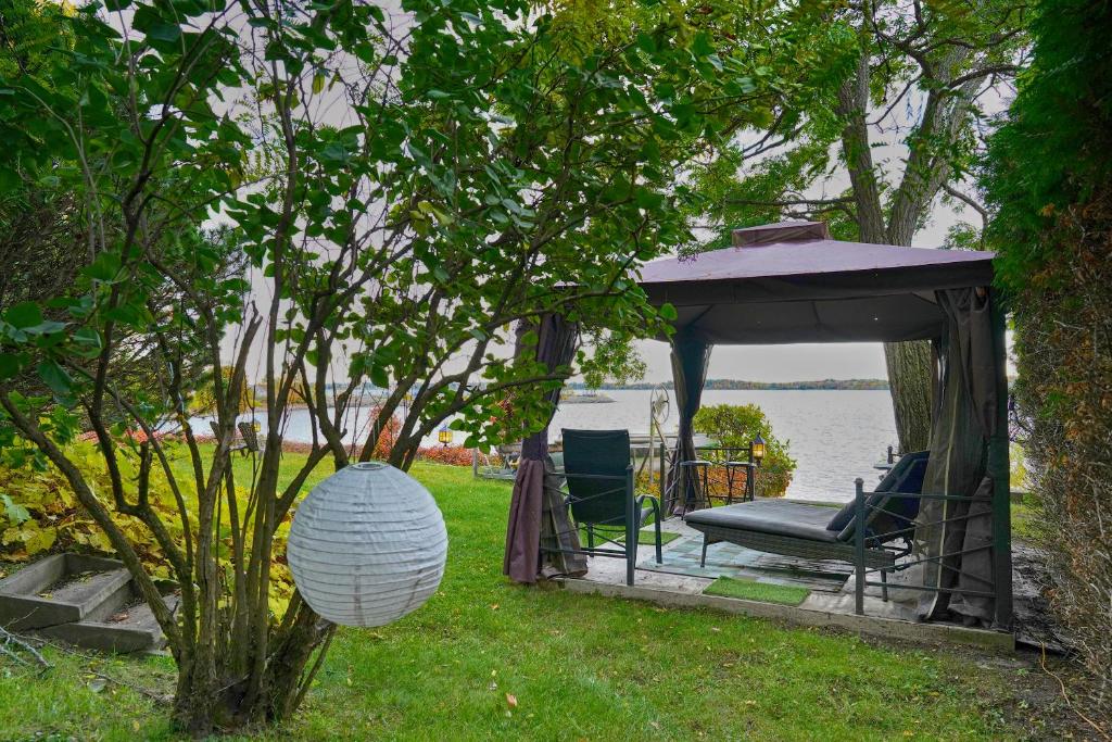 a gazebo with a chair in the grass next to the water at Gîte le 308 Chambre bord de l'eau oka in Oka