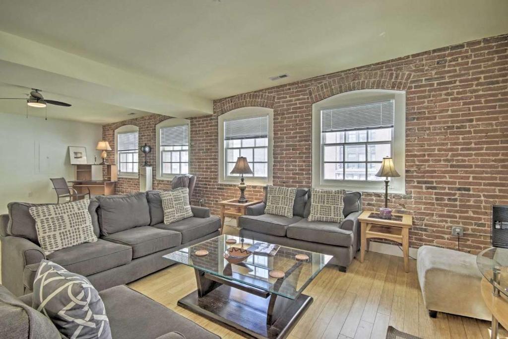 a living room with a couch and a brick wall at Chase Apartments at Light Street - Baltimore Inner Harbor & Convention Center Free indoor parking in Baltimore