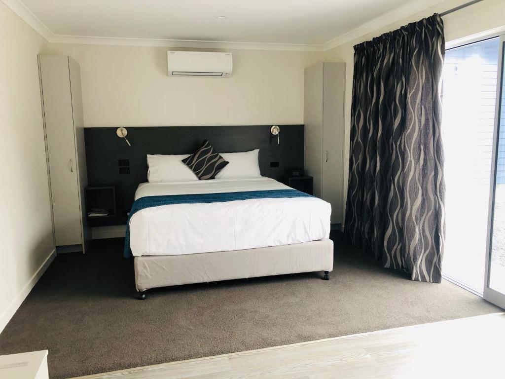 - une chambre avec un grand lit et une fenêtre dans l'établissement Thornton Lodge Motel, à  Waipukurau
